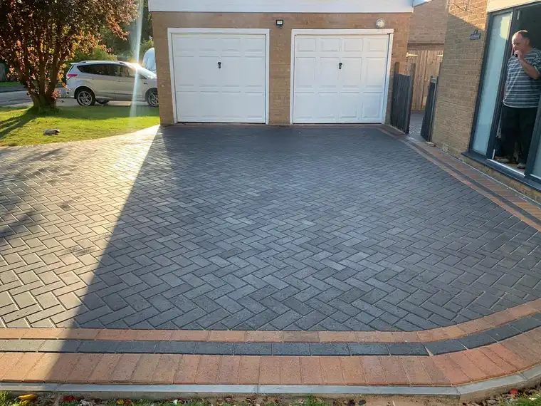 Grey herringbone block paving up to a double garage