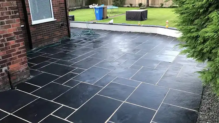 Black limestone patio beside white rendered walls