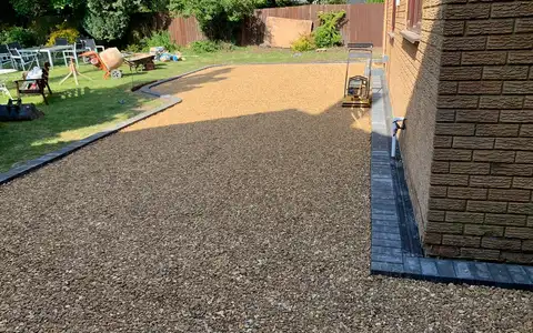Golden gravel driveway beside a brick house