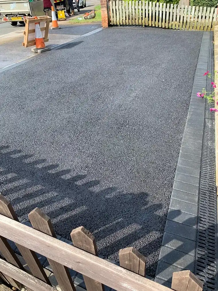 Freshly laid tarmac driveway with drainage channel