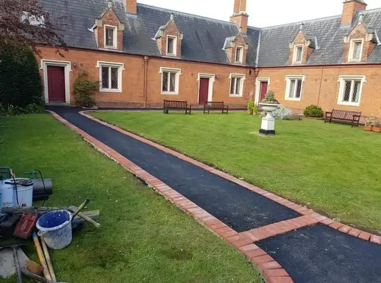 Tarmac paths with red brick borders across lawned gardens