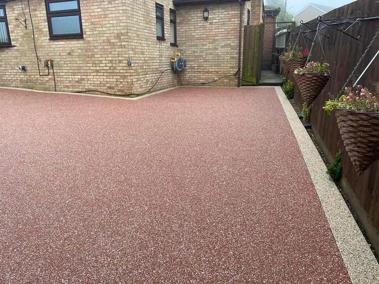 Red resin bound driveway in front of a brick house