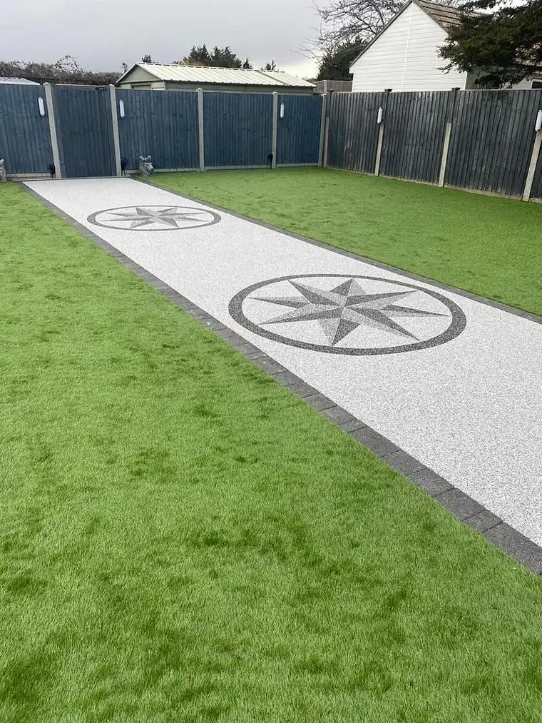Silver resin path with compass star inlays beside artificial lawn